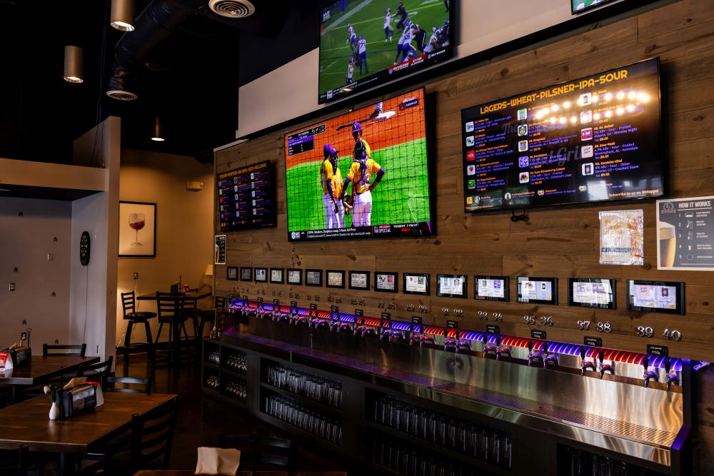 Sports bar in Auburn, AL with large screens displaying games and a self-serve beer wall.